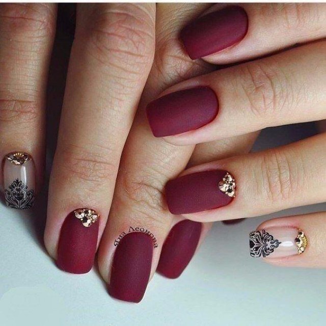 Святковий бордовий манікюр з матовим фінішем: золото, стрази та штампування на овальних нігтях