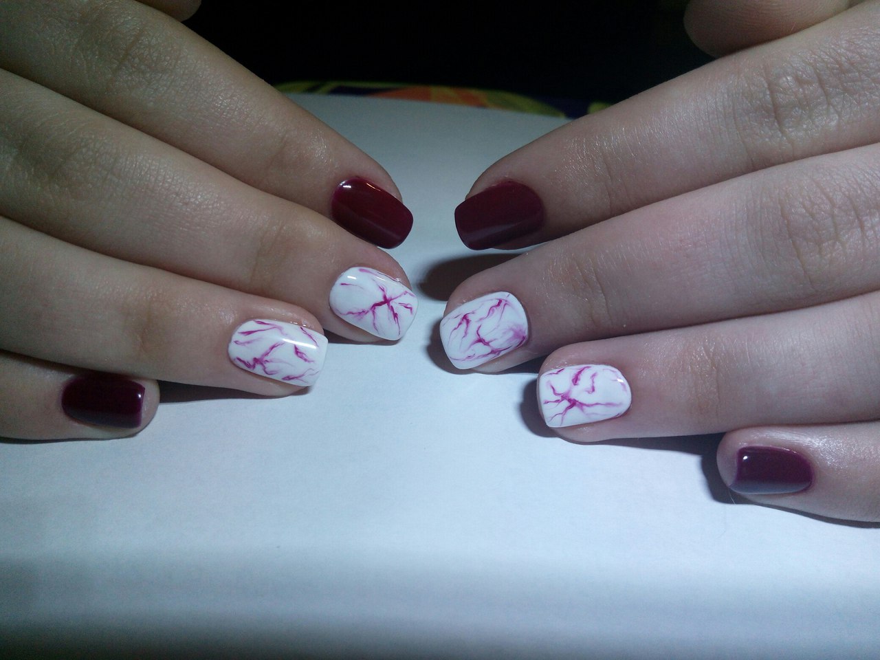 Бордовий манікюр з мармуровим дизайном: круглі короткі нігті