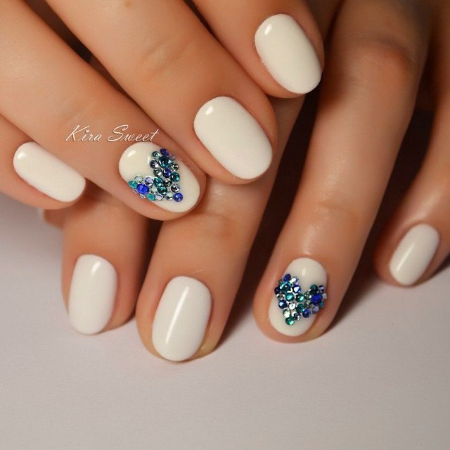 Білий манікюр з 3D елементами та блискучими стразами на овальних нігтях