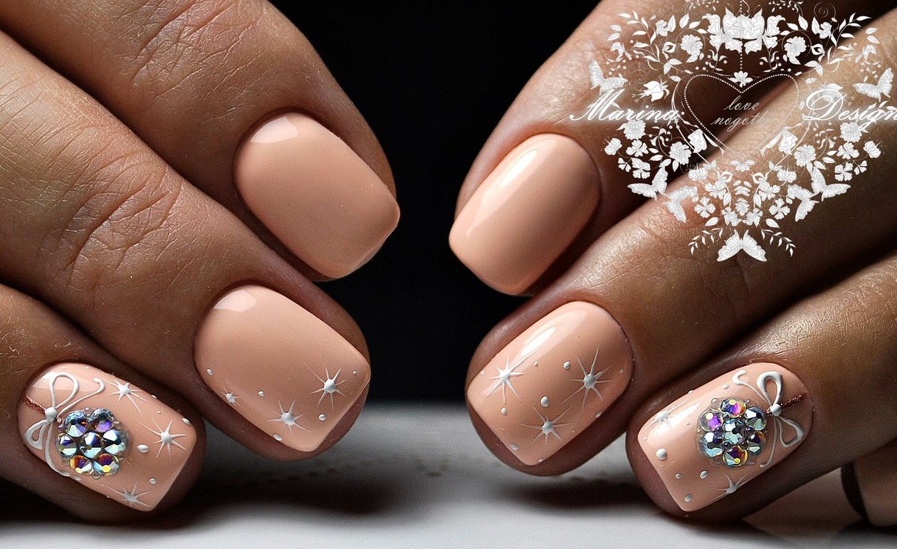 Бежевий манікюр з білим 3D розписом та стразами на овальних нігтях