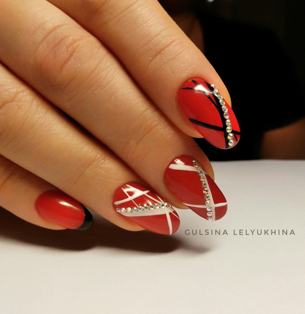Червоний манікюр з чорною геометрією та блискучими стразами на мигдалеподібних нігтях