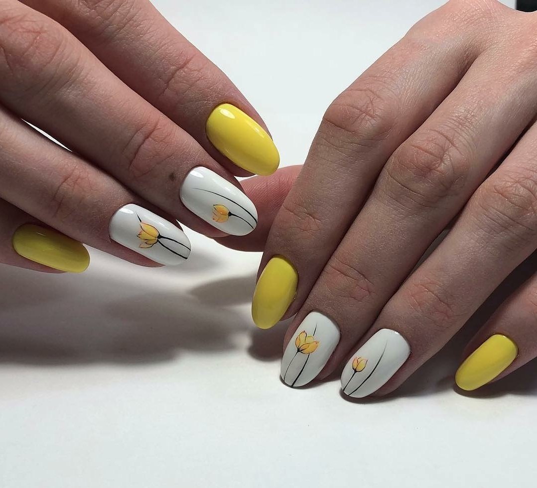 Жовтий манікюр з білим квітковим ручним розписом на мигдалеподібних нігтях