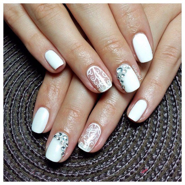Овальні нігті: білий гель-лак, сріблястий розпис та стрази – святковий максималізм